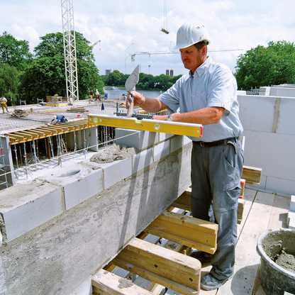 Werkfit Maurer bei der Arbeit mit der gelben Wasserwaage Type 96-2 K auf einer Baustelle