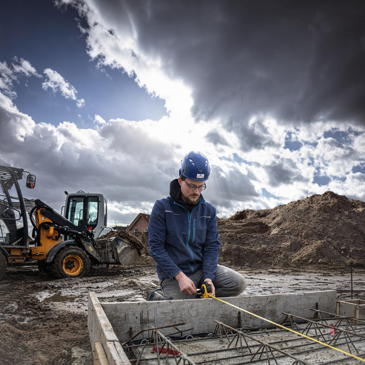 Werkfit Kapselbandmaß LBM 2000 STEEL in Anwendung durch einen Bauarbeiter auf einer schlammigen Baustelle