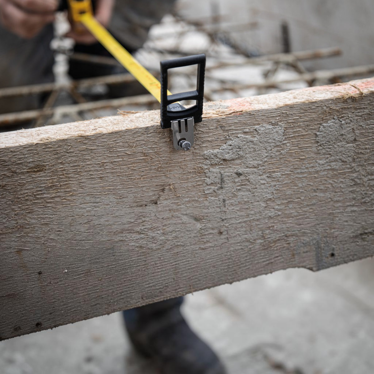 Werkfit Kapselbandmaß LBM 2000 STEEL mit gelbem Stahlband beim Messen einer Holzschalung auf einer Baustelle