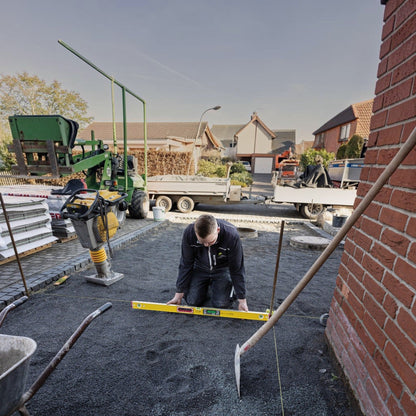 Handwerker von Werkfit nutzt die gelbe elektronische Wasserwaage TECH 196 DL zur präzisen Ausrichtung auf einer Baustelle