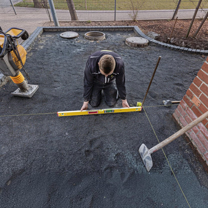 Handwerker nutzt Werkfit Elektronik-Wasserwaage TECH 196 DL zur Ausrichtung von Pflastersteinen auf einer Baustelle