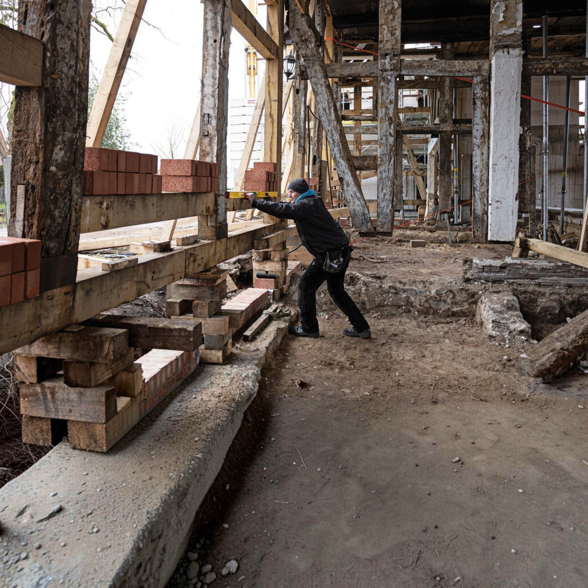 Handwerker nutzt Werkfit Elektronik-Wasserwaage TECH 196 DL an einem Holzbalken auf einer Baustelle