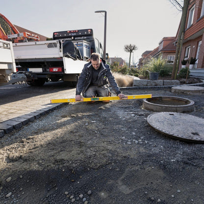 Handwerker von Werkfit nutzt die gelbe Elektronik-Wasserwaage TECH 196 DL zur Nivellierung auf einer Baustelle