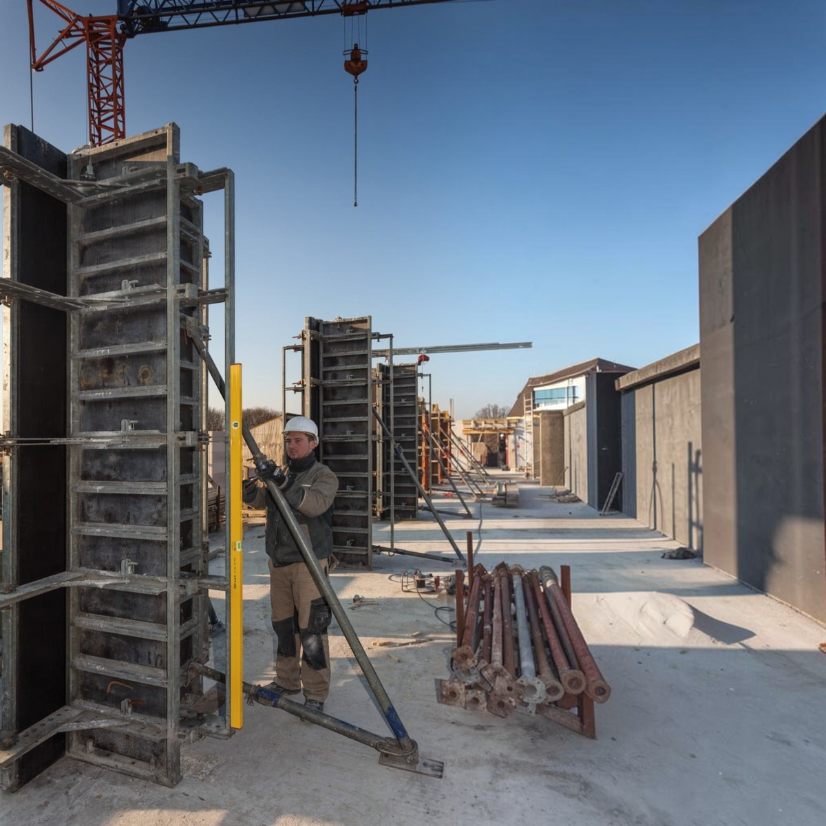 Handwerker von Werkfit nutzt die gelbe Wasserwaage Type 80 ASM zur Ausrichtung einer Schalung auf der Baustelle