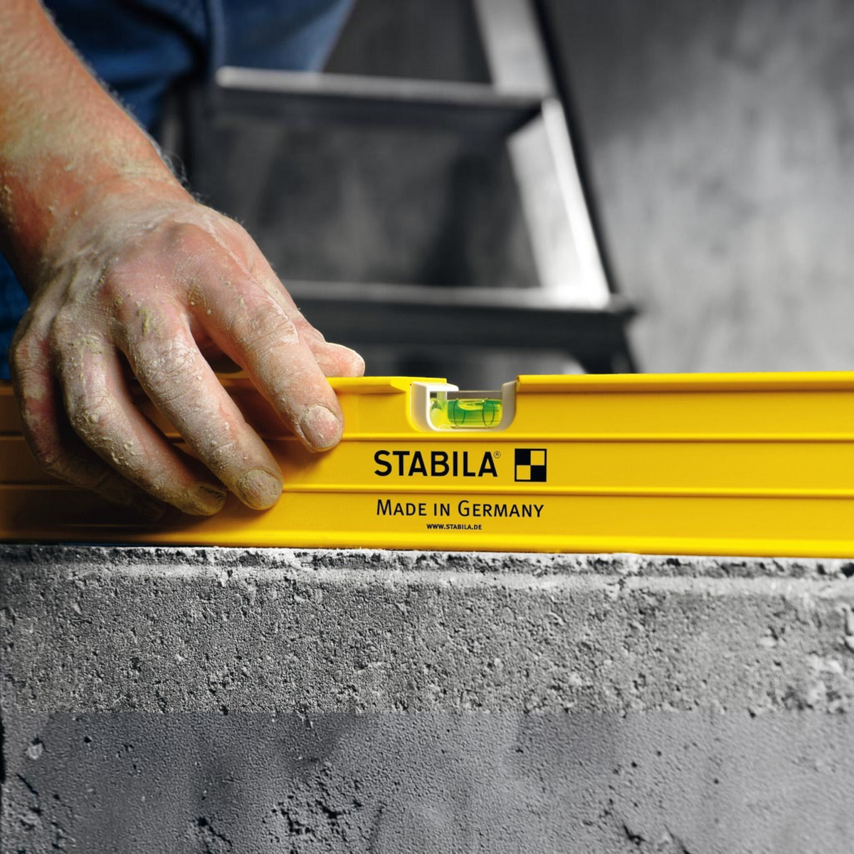 Werkfit Stabila Wasserwaage Typ 96-2 in Gelb bei der Anwendung auf einer Betonoberfläche durch einen Handwerker