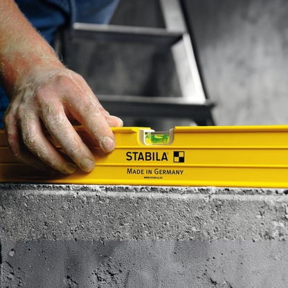 Werkfit Stabila Wasserwaage Typ 96-2 in Gelb bei der Anwendung auf einer Betonoberfläche durch einen Handwerker