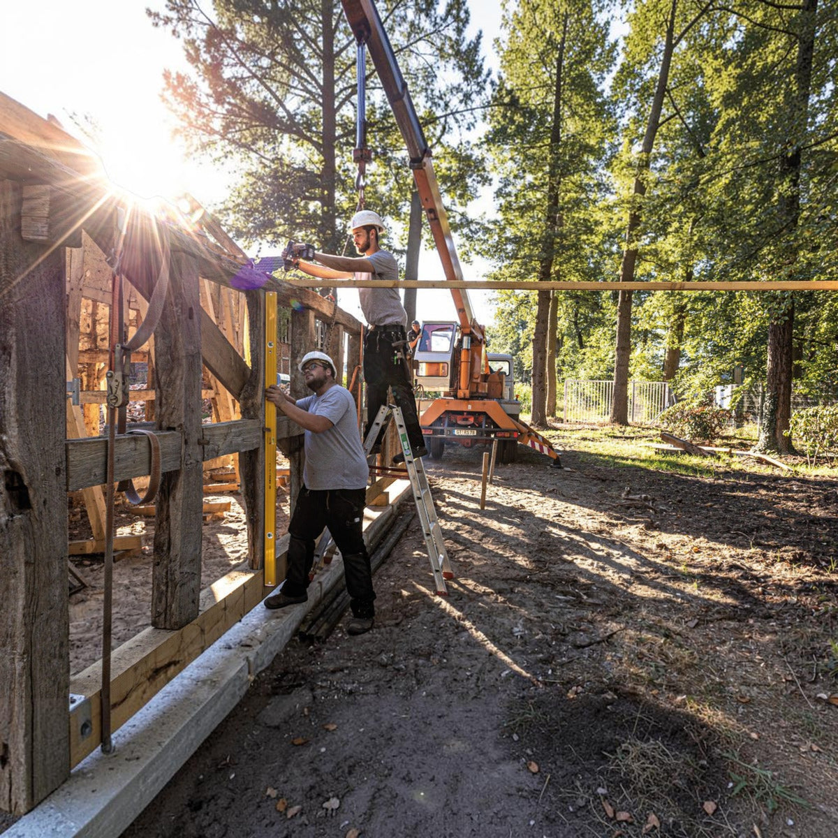 Zwei Handwerker nutzen eine gelbe Werkfit Wasserwaage Type 96-2 beim Bau eines Holzrahmens auf einer Baustelle.