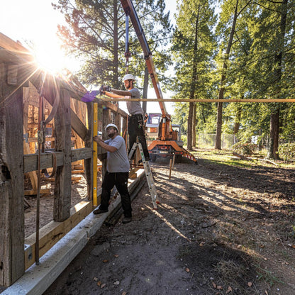 Zwei Handwerker nutzen eine gelbe Werkfit Wasserwaage Type 96-2 beim Bau eines Holzrahmens auf einer Baustelle.