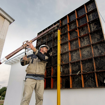 Werkfit Wasserwaage Type 96-2 M in Gelb bei der Arbeit an einer Schalung durch einen Handwerker mit Schutzhelm