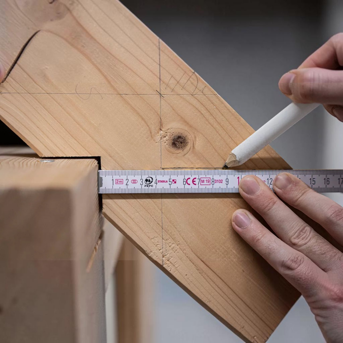 Werkfit Holz-Gliedermaßstab Typ 1407 beim Anzeichnen einer Markierung auf einem Holzbalken mit einem Bleistift